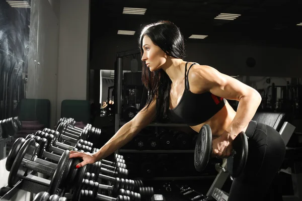 性感的女人做与哑铃在健身房锻炼。锻炼背部和肱三头肌 — 图库照片