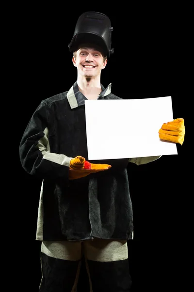 Handsome welder holding a blank form. isolated on black background — Stock Photo, Image