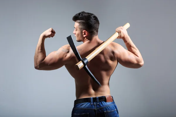 Muscular man holding pickaxe — Stock Photo, Image