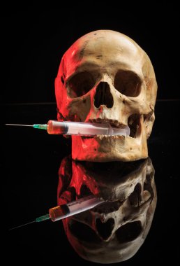 Skull and syringe of yellowish liquid. concept drugs clipart