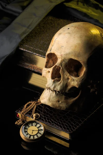 Cráneo humano en un libro al lado del reloj. concepto de magia negra —  Fotos de Stock