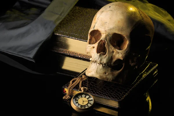 Crânio humano num livro ao lado do relógio. conceito de magia negra — Fotografia de Stock