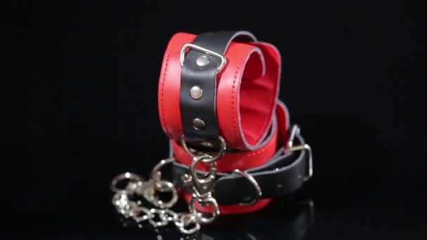 Red leather handcuffs in black background. sex toy — Stock Video