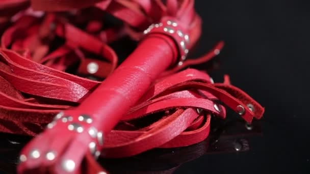 Látigo de cuero rojo para juegos BDSM. sobre un fondo negro. juguete sexual — Vídeos de Stock