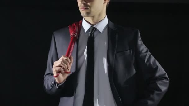 Man in een pak een zweep voor sex spelletjes te houden. rode huid. liefde speelgoed — Stockvideo