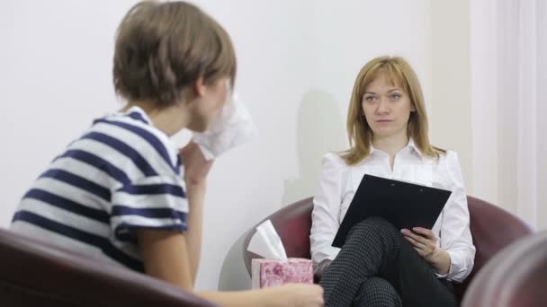 Psicóloga haciendo notas durante la sesión de terapia psicológica. chica triste — Vídeos de Stock