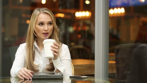 Mujer joven y feliz bebiendo café o té y usando una tableta en una cafetería. mujer de negocios en un almuerzo de negocios — Vídeo de stock