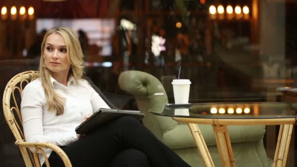 Жінка використовує сенсорний екран планшетного комп'ютера в кафе п'є каву — стокове відео