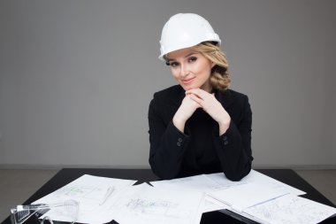 Woman architect with drawings. Beautiful girl in a building helmet
