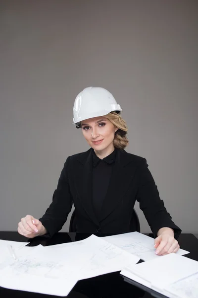 Arquitecta con dibujos. Hermosa chica en un casco de edificio — Foto de Stock