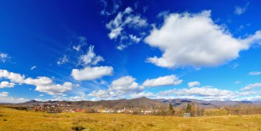Ardı ardına bahar manzarası, yoğun mavi gökyüzü ve bulutlar.