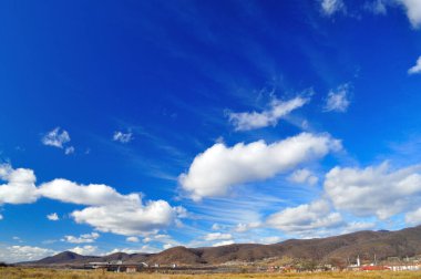 Ardı ardına bahar manzarası, yoğun mavi gökyüzü ve bulutlar.