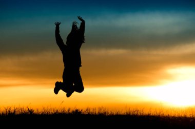 Gün batımında atlayan kız silueti. 