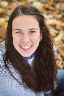 Parktaki sonbahar kızı kameraya doğru gülümsüyor.