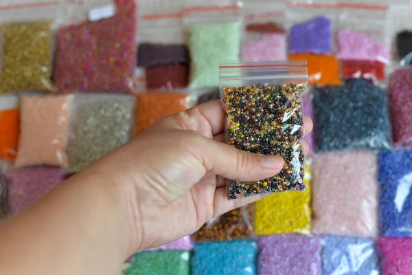 Multicolored beads close-up in bulk and packed in a bag or jar, for the work of needlewomen