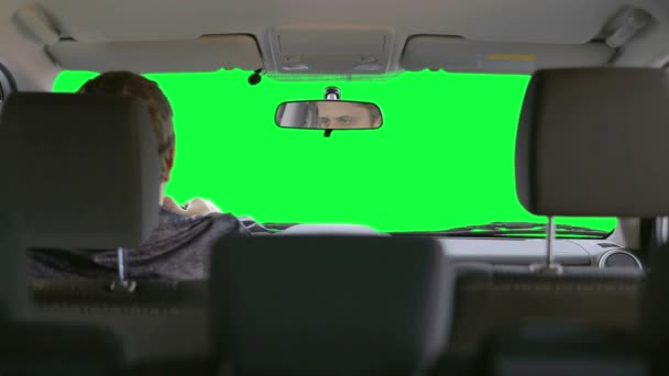 Homem dirige um carro contra um fundo verde — Vídeo de Stock