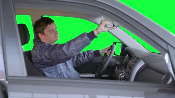 El hombre conduce un coche contra un fondo verde — Vídeo de stock