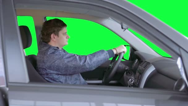 Man drives a car against a green background — Stock Video