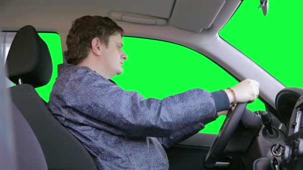 Muž jezdí autem na zeleném pozadí — Stock video