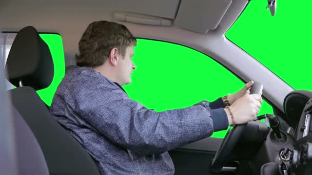 Чоловік водить машину на зеленому тлі — стокове відео