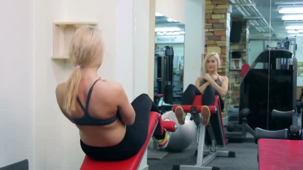 Mujer joven entrenando en un gimnasio — Vídeos de Stock