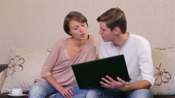Casal jovem com um laptop em um sofá — Vídeo de Stock