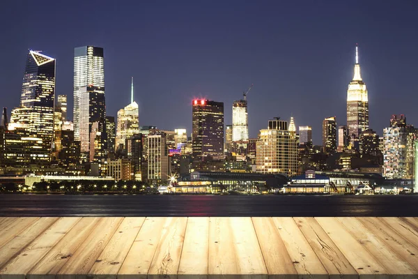 Wooden table top with beautiful New York skyline at night on background, mockup
