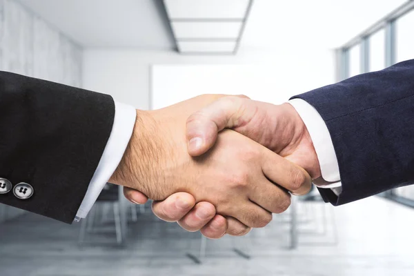 Два бизнесмена пожимают руки на фоне яркого конференц-зала, инвестиционной концепции, крупным планом — стоковое фото