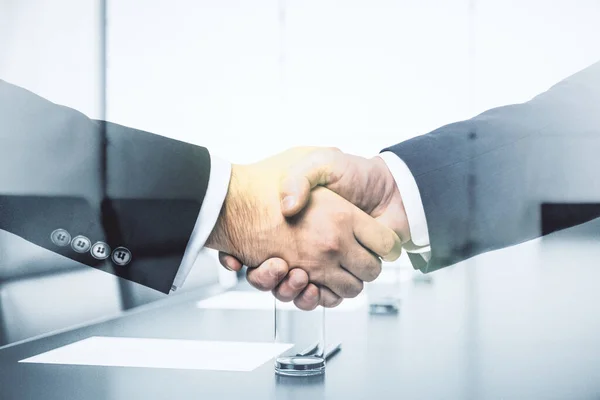 Handshake of two businessmen on boardroom interior background, deal and trading concept. Multiexposure