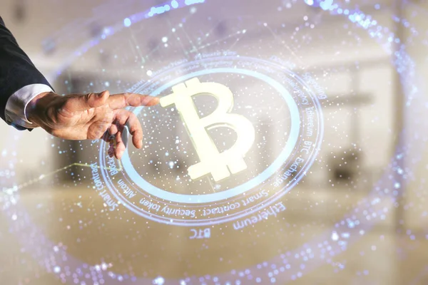 Dvojité vystavení mužské ruky tlačí na kreativní Bitcoin symbol hologram na rozmazaném kancelářském pozadí. Koncept kryptoměny — Stock fotografie