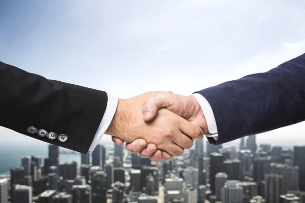Два бизнесмена пожимают руки на фоне современного городского пейзажа, концепция сделки, крупным планом — стоковое фото