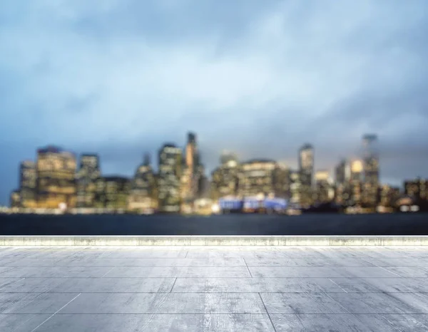 Terraplén sucio de hormigón vacío en el fondo de un hermoso horizonte borroso de la ciudad de Nueva York por la noche, se burlan — Foto de Stock
