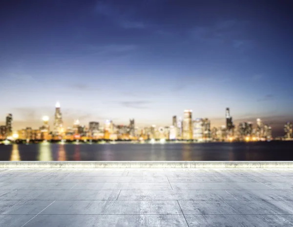 Terraplén sucio de hormigón vacío en el fondo de un hermoso horizonte borroso de la ciudad de Chicago por la noche, se burlan — Foto de Stock