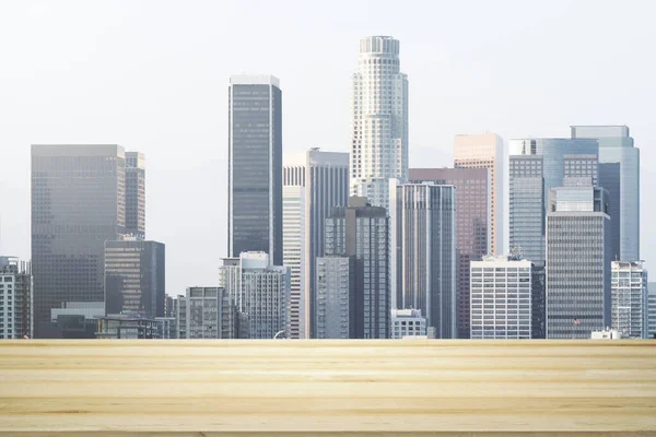 Empty wooden tabletop with beautiful Los Angeles skyscrapers at daytime on background, mock up