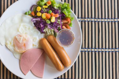 Kızarmış yumurta, sosis, jambon ve mix yemek üzerinde sebze