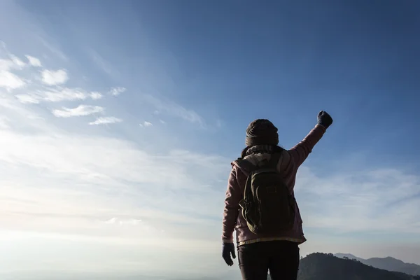 Woman with backpack standing on top of a mountain with raised ha — Stock Photo, Image