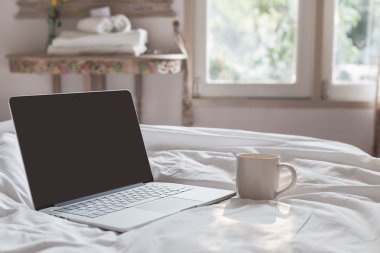 Kahve fincanı ve sabah saat yatakta üstünde laptop