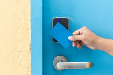 Mavi otel keycard elektrikli kapı önünde tutan el