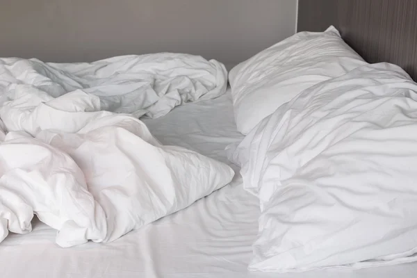 Sábanas blancas y almohada, concepto de cama desordenado —  Fotos de Stock