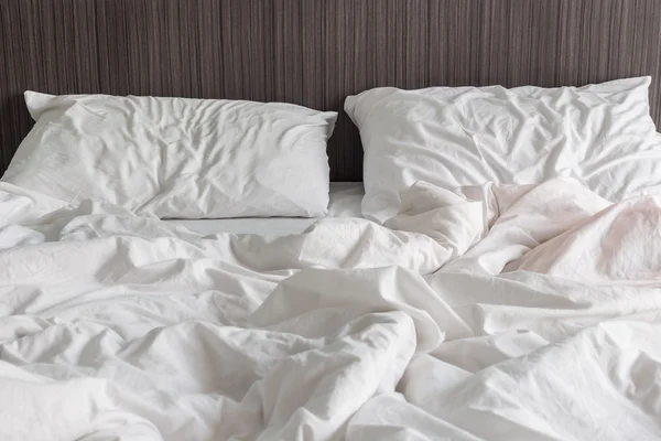 Sábanas blancas y almohada, concepto de cama desordenado —  Fotos de Stock