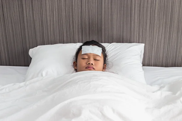 Niños con fiebre fría en la frente y durmiendo en la cama — Foto de Stock