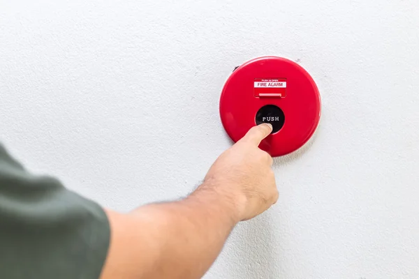 Hand mit Finger drückt roten Feuermelder an die Wand — Stockfoto