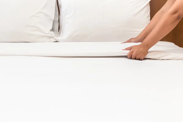 Hand instellen van witte bed blad in hotelkamer — Stockfoto
