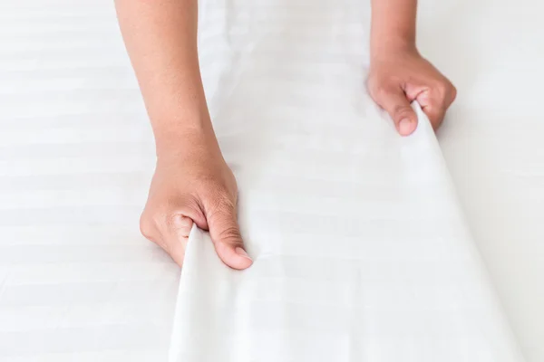 Mano establecer sábana blanca en la habitación de hotel — Foto de Stock