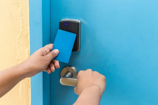 Kezében kék hotel kulcskártya elektromos ajtó előtt — Stock Fotó