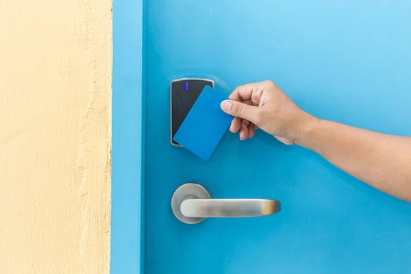 Hand hält blaue Hotel-Schlüsselkarte vor elektrischer Tür — Stockfoto