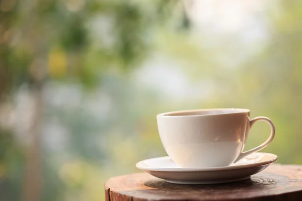 Witte koffiekopje op tafel in de tuin met onscherpte licht bokeh — Stockfoto