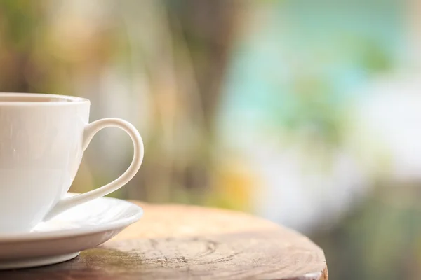 Taza de café blanco en la mesa en el jardín con luz borrosa bokeh —  Fotos de Stock