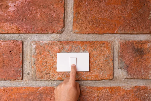 Hand turn off light switch on the red wall — Stock Photo, Image
