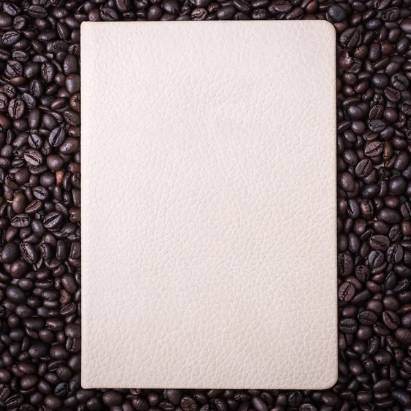 Grãos de café e livro de notas sobre fundo de madeira — Fotografia de Stock